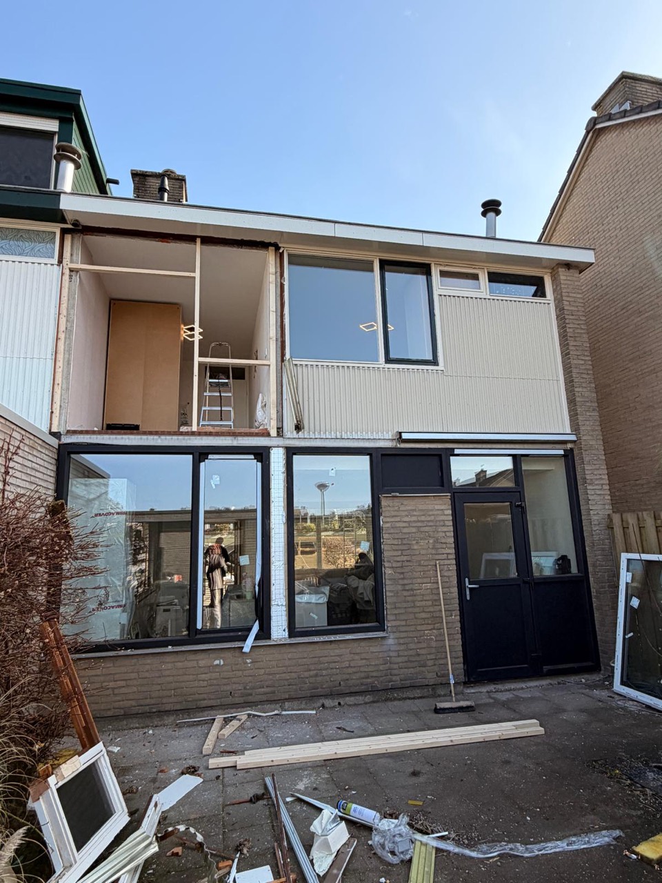 Beneden zijn de nieuwe kozijnen geplaatst. Boven wordt de bestaande houten gevel verwijderd.