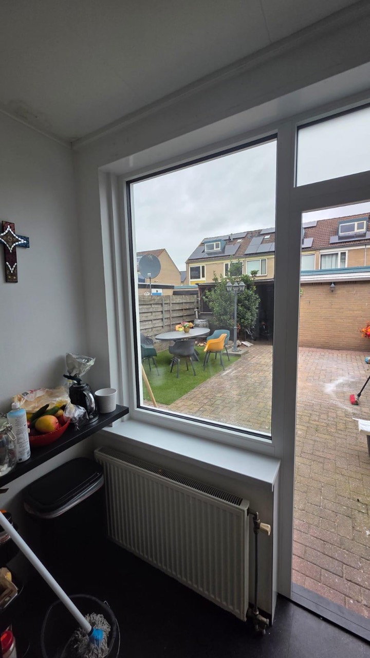 Witte afwerking bij een raam, vensterbank en achterdeur.